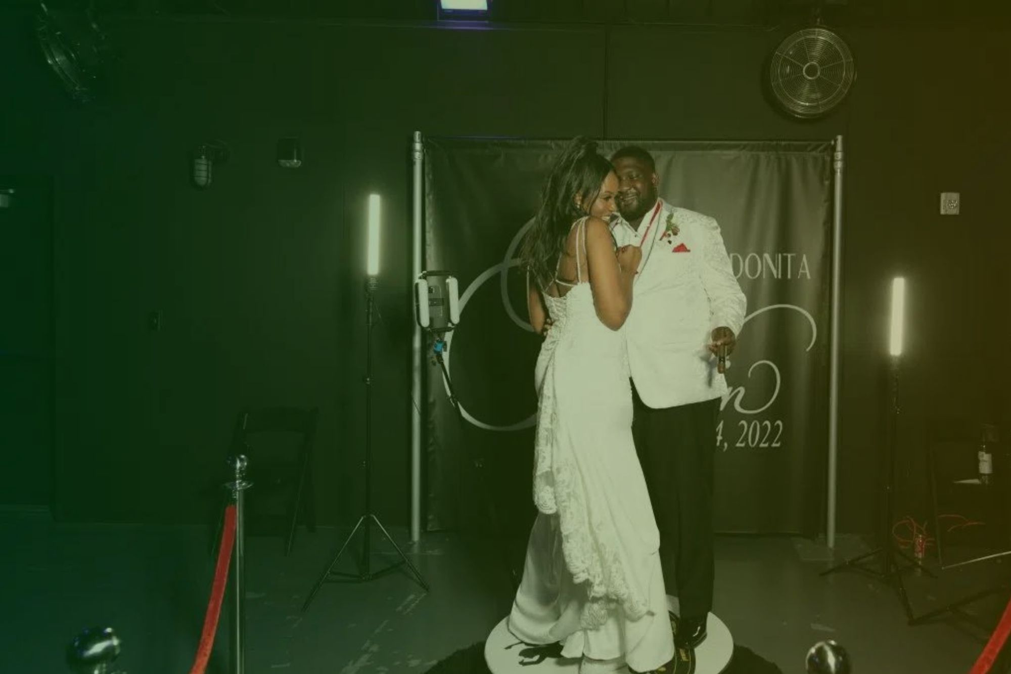 A couple during their wedding standing on a 360 photobooth